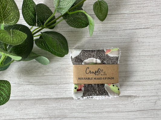 A sustainable Star Wars Grogu makeup pad by Crafts by Kate, wrapped in a brown paper label, lies on a light wooden surface with green leaves, representing the future of reusable make-up remover pads.