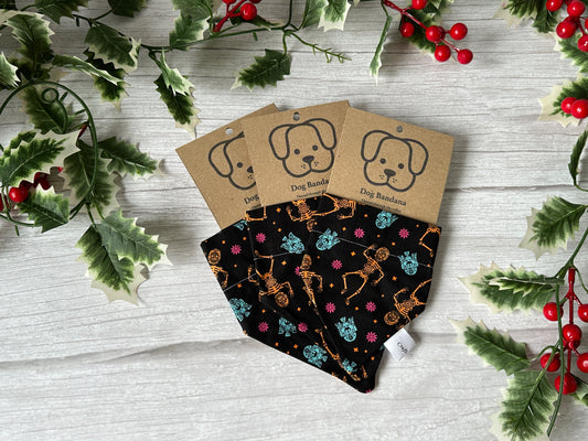 Three handcrafted black cotton pet bandanas by Crafts by Kate feature Star Wars Christmas designs with collar attachments. Each is displayed on a cardboard backing with a dog illustration, framed by holly and red berries on a white wooden surface.