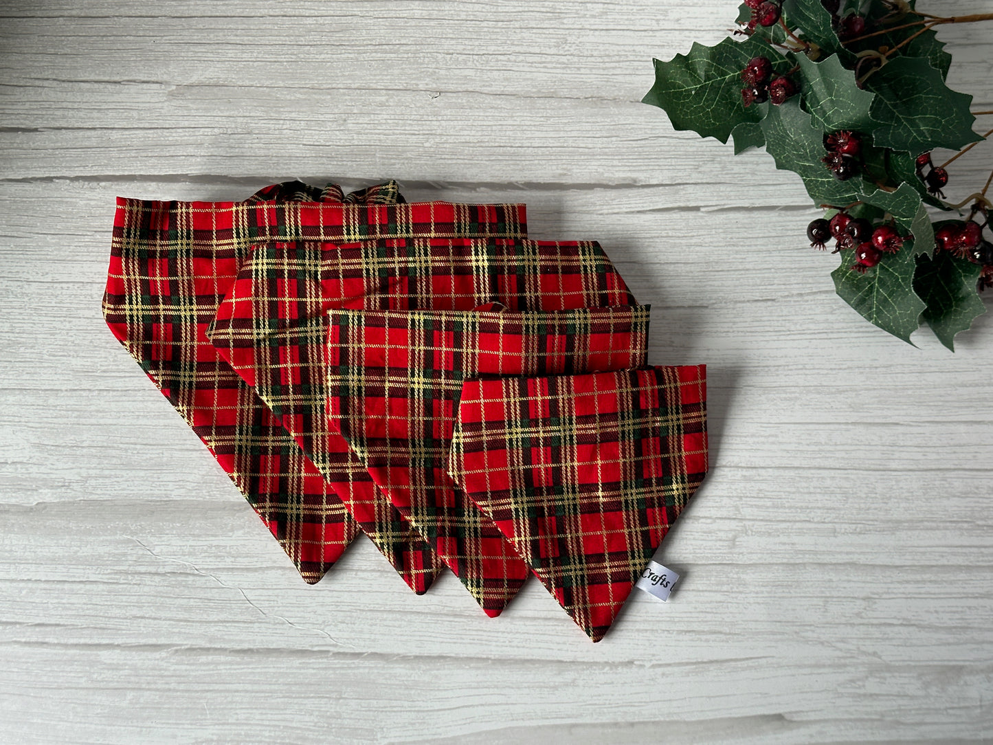 Five Crafts by Kate Cotton Pet Scrunchie Bandana - Red & Gold Tartan in assorted sizes are displayed on a light wooden surface, accented by holly and red berries for a festive touch to your pet's accessory collection.