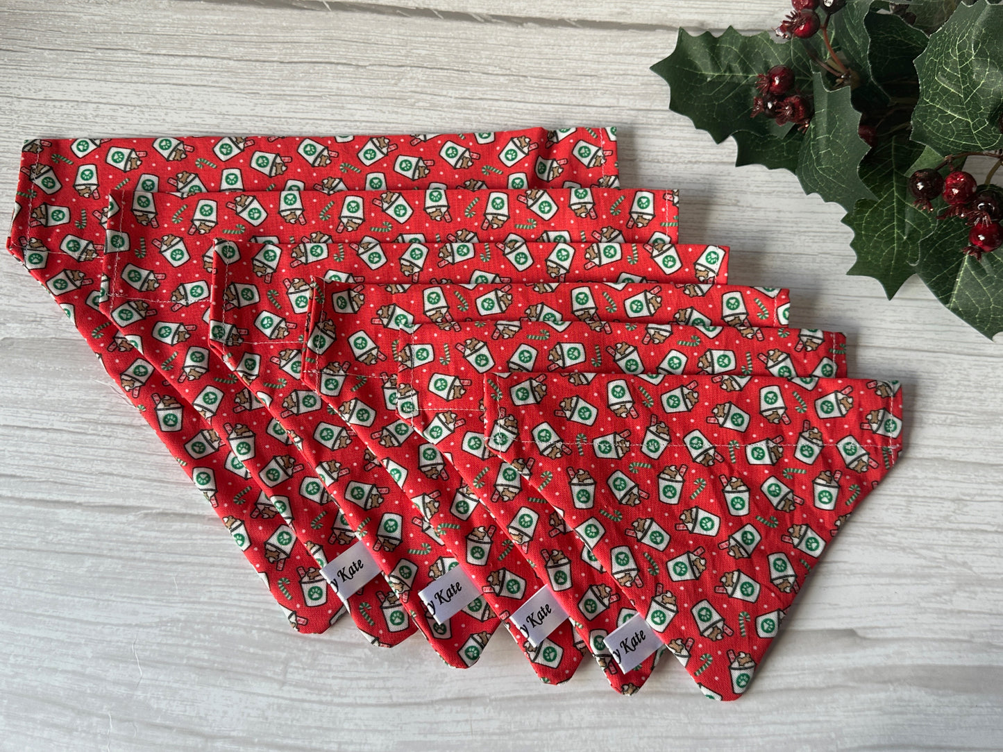 Six handcrafted red “Christmas Pupcup” Cotton Pet Bandanas with collar attachments by Crafts by Kate, featuring festive green and white prints, are displayed on light wood with holly—ideal “1-4L” holiday accessories for your pup.