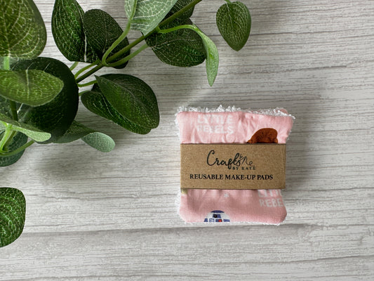 A neatly folded stack of sustainable Crafts by Kate Cotton Reusable Make-up Remover Pads - Star Wars Little Rebel, on a wooden surface. A green plant with round leaves in the upper left corner enhances the eco-friendly aesthetic.