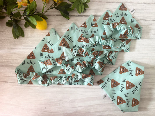 Five mint green Cotton Pet Scrunchie Bandanas by Crafts by Kate, each printed with cartoon poop emojis and "lil shit," are arranged on a light wood surface with greenery and yellow lemons nearby.