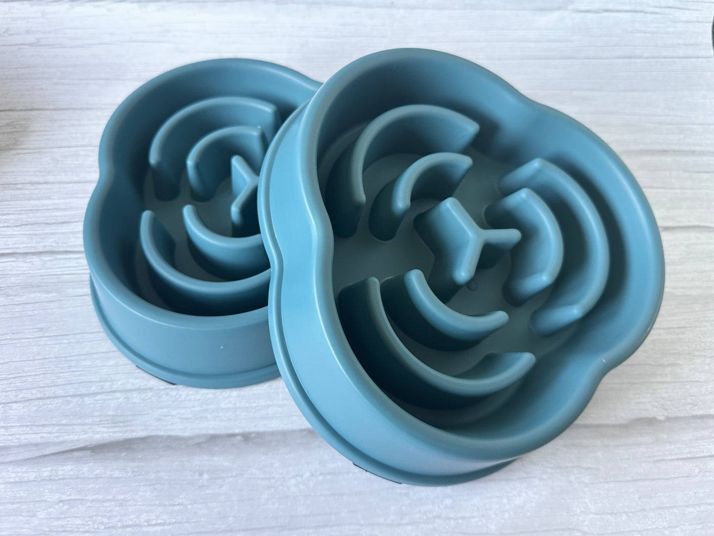 Two blue silicone Slow Feeder Pet Bowls by Crafts by Kate sit on a white wooden surface, featuring spiral raised patterns to promote better digestion by slowing your pet's eating pace.
