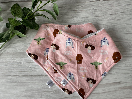 Cotton & Terry Towelling Baby Bandana Bibs - Star Wars Little Rebels by Crafts by Kate, showcasing cartoon characters, are neatly arranged on a light wooden surface alongside green leaves.